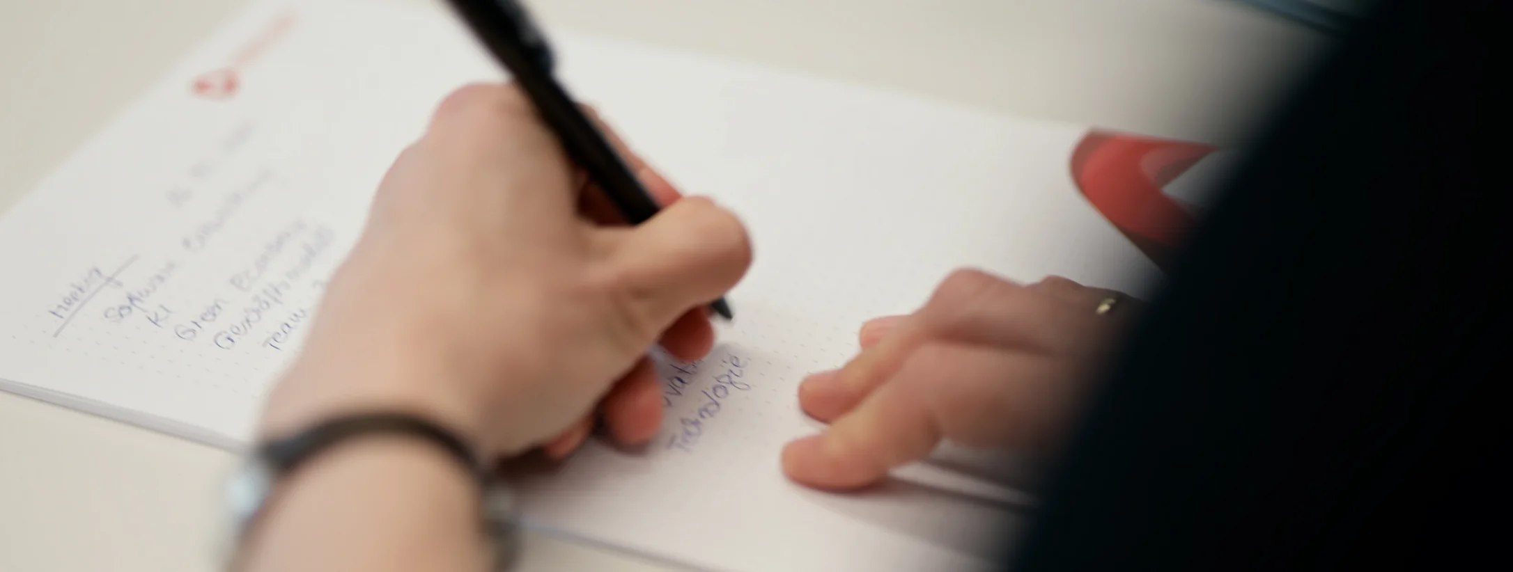Eine Person schreibt Notizen auf ein Blatt Papier